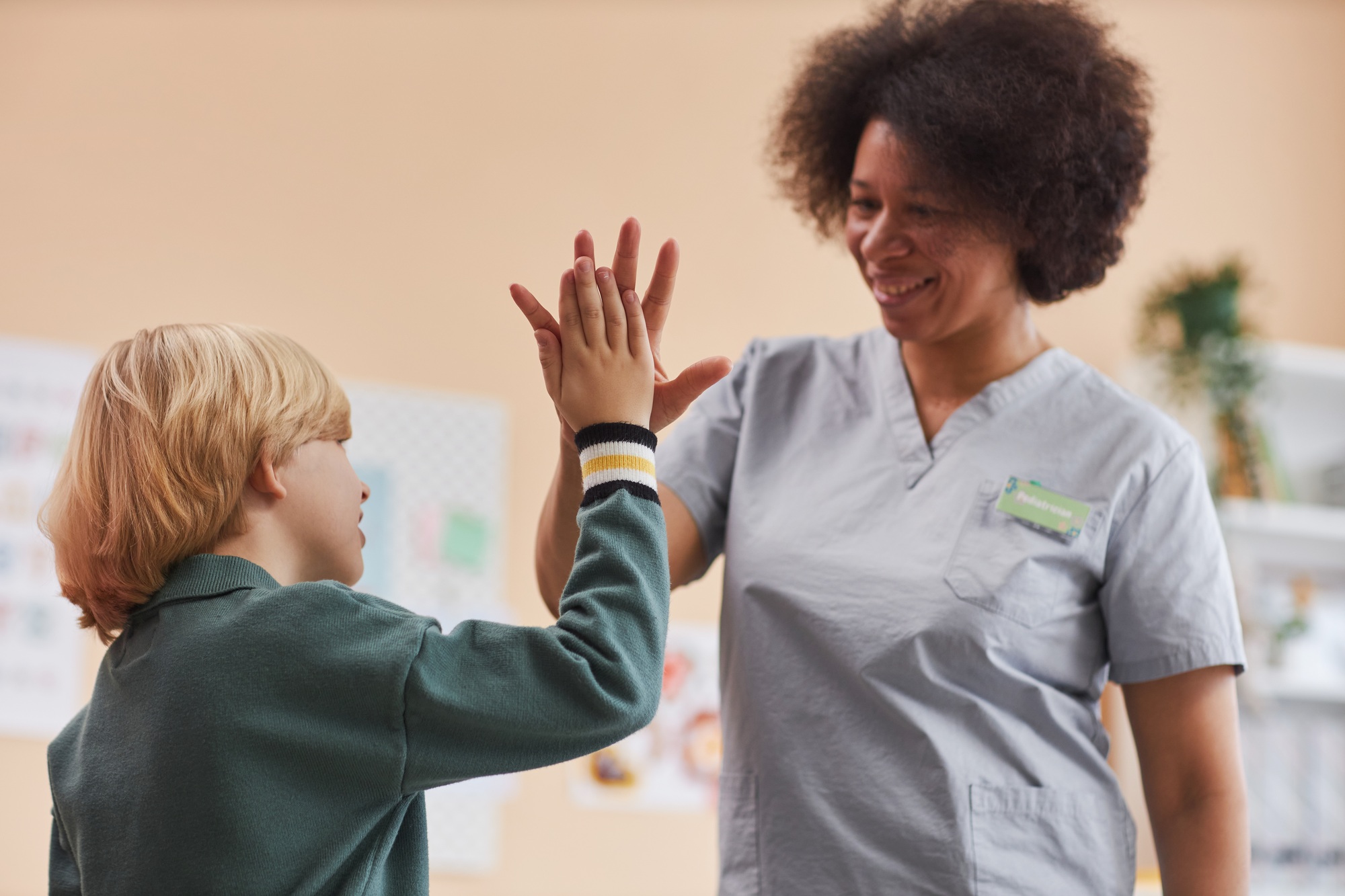 Black Nurse High Five with Little Boy in Clinic