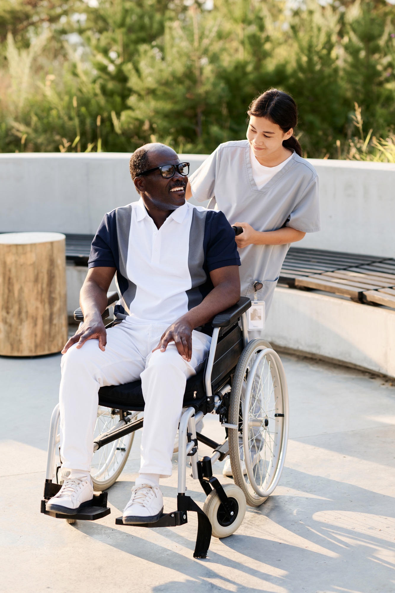 Caregiver walking outdoors with senior man with disability