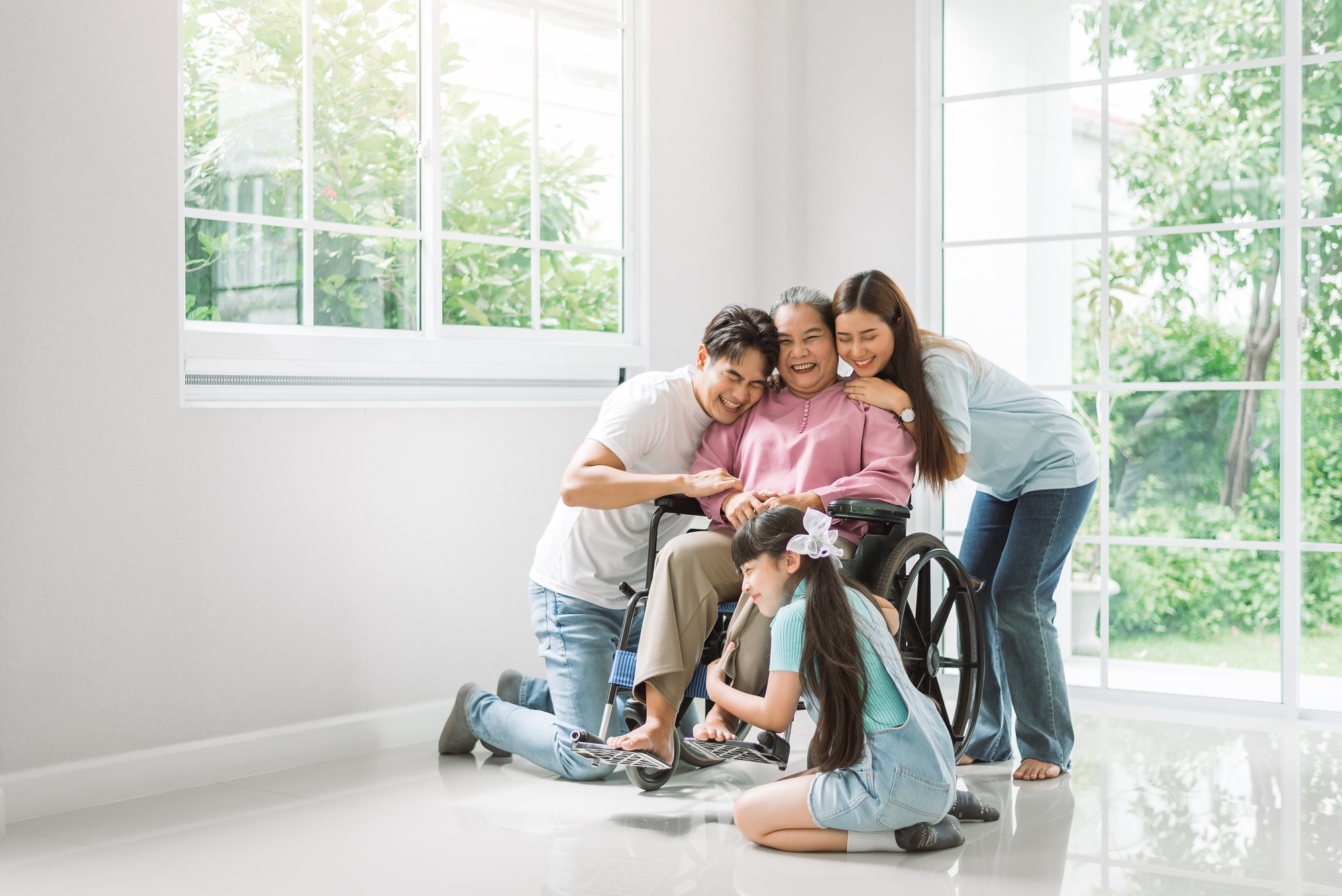 Happy asian family spending time together at new home, grandmother on wheelchair with family members